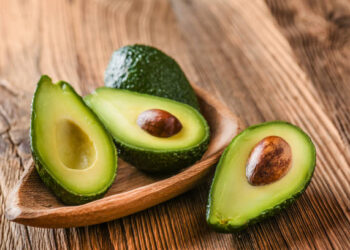 Avocado on old wooden table in bowl. Halfs of avocados fresh fruits healthy food.